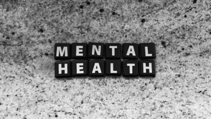 Scrabble tiles spelling out "mental health" over a textured grey and white background.