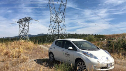A BC Hydro car is parked in front of some large power lines.