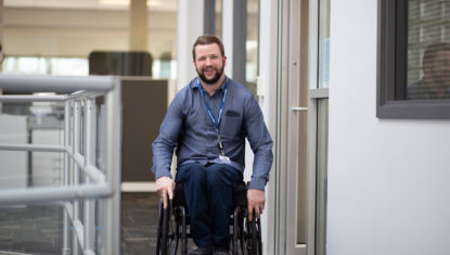 Adam is wheeling his manual wheelchair through the BC Transit main office.