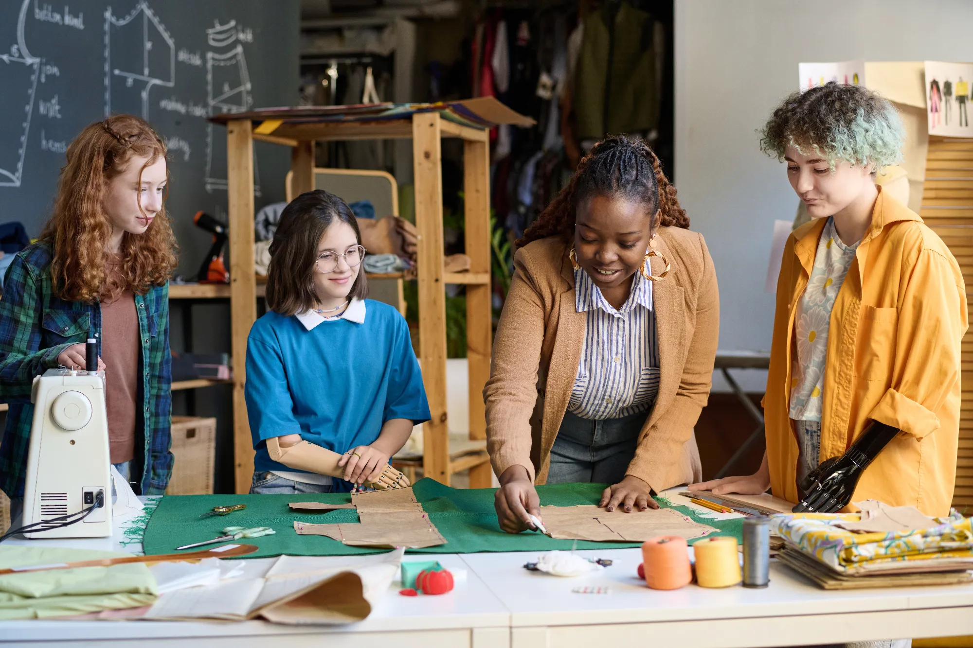 Portrait of Black young woman teaching diverse group of girls making clothing patterns in sewing class.