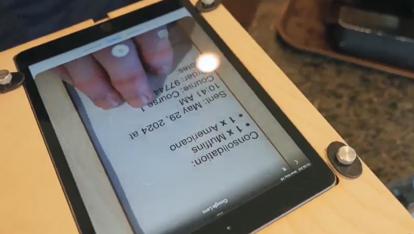 Screenshot from CanAssist’s video, featuring an employee magnifying a barista receipt via an iPad built into a scanner-platform and the technology reading it aloud to the employee’s headset.